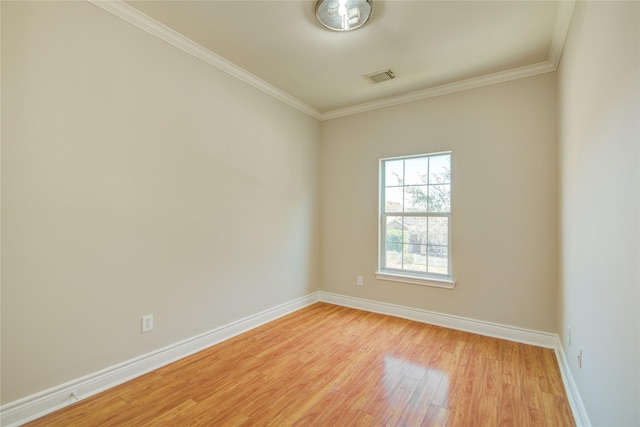 spare room with light wood-type flooring, visible vents, baseboards, and crown molding