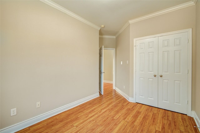 unfurnished bedroom with a closet, baseboards, ornamental molding, and light wood finished floors