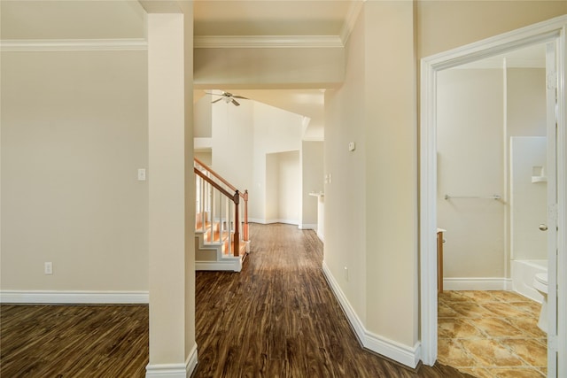 hall with baseboards, wood finished floors, ornamental molding, and stairs