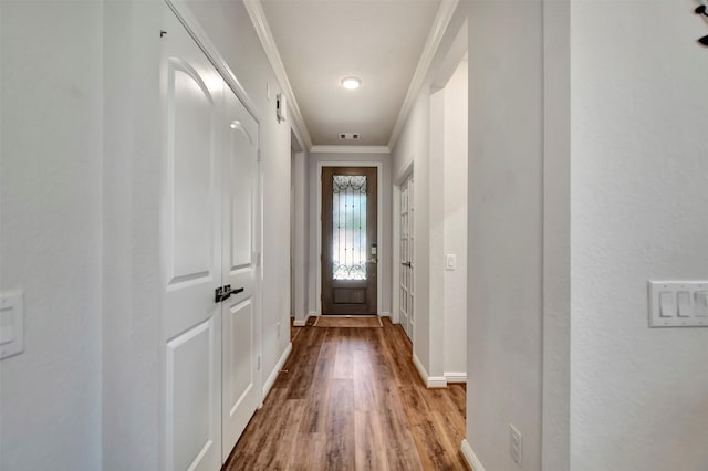 doorway featuring visible vents, wood finished floors, baseboards, and ornamental molding