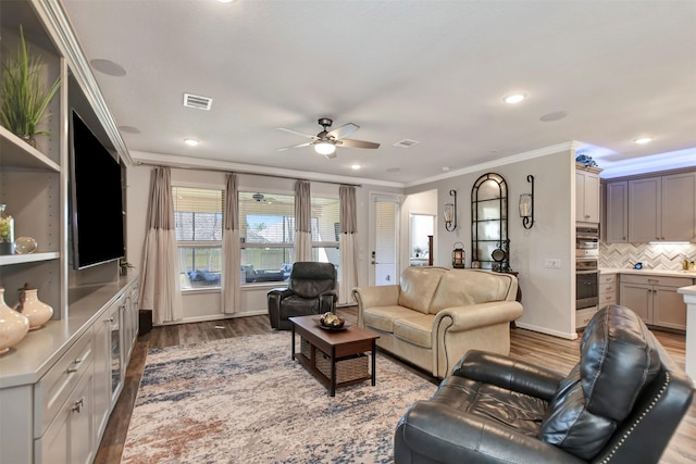 living room featuring light wood-type flooring, baseboards, visible vents, and ornamental molding