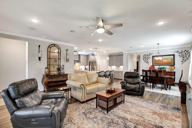 living room featuring recessed lighting, visible vents, ornamental molding, and wood finished floors