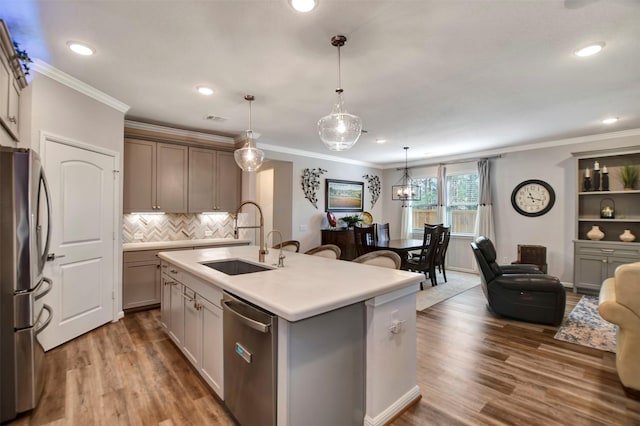 kitchen with ornamental molding, appliances with stainless steel finishes, wood finished floors, and a sink