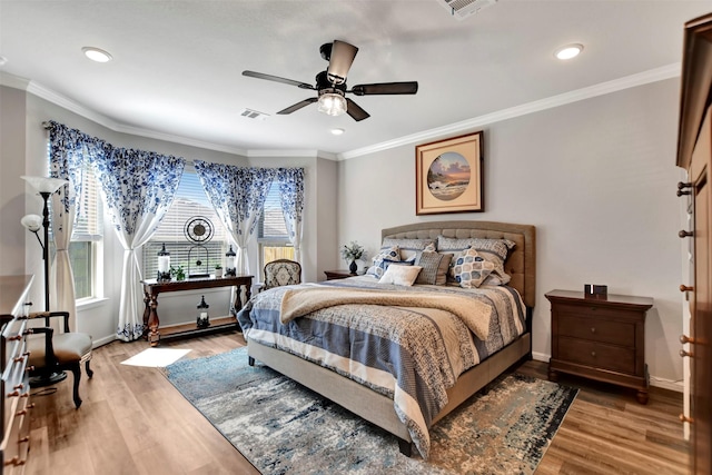 bedroom with visible vents, crown molding, baseboards, and wood finished floors