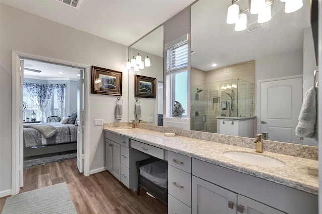 bathroom with a healthy amount of sunlight, wood finished floors, double vanity, a sink, and a shower stall