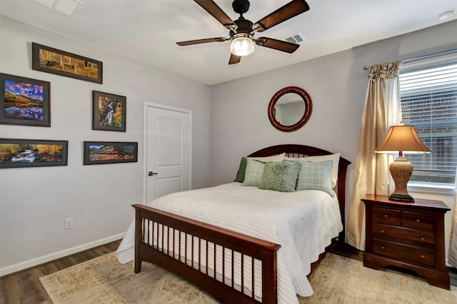 bedroom featuring visible vents, a ceiling fan, baseboards, and wood finished floors