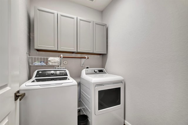 laundry area featuring cabinet space, independent washer and dryer, and a textured wall