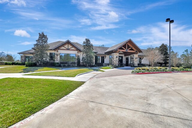 view of front facade with stone siding, a front lawn, and driveway