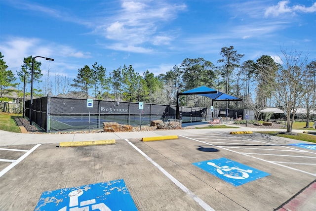 uncovered parking lot with a tennis court and fence