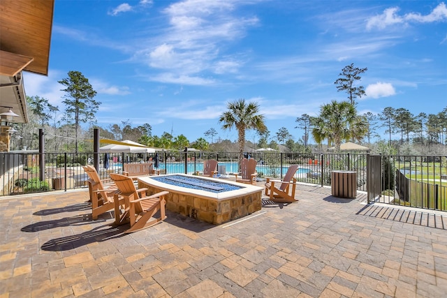 view of patio / terrace featuring a community pool, a fire pit, and fence