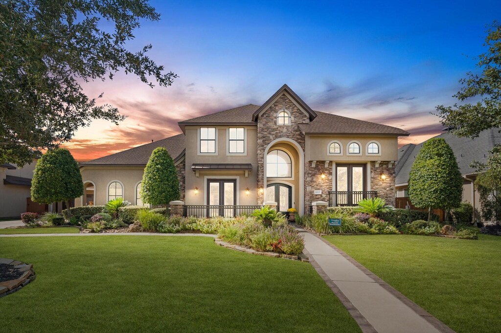 10115 Llano River Ln, Cypress, TX 77433 - view of front of house with stone siding, stucco siding, french doors, and a lawn