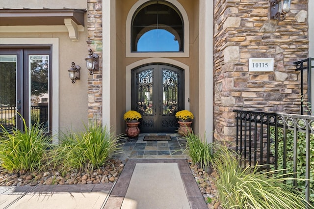 entrance to property with french doors, stone siding, and stucco siding