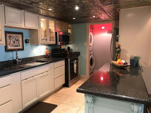 kitchen featuring stacked washer / dryer, glass insert cabinets, appliances with stainless steel finishes, an ornate ceiling, and a sink