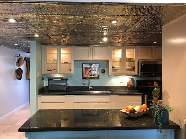 kitchen with dark stone countertops, baseboards, a sink, electric stove, and stainless steel microwave