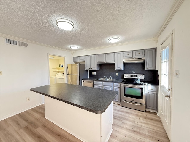 kitchen with visible vents, gray cabinetry, dark countertops, appliances with stainless steel finishes, and washing machine and clothes dryer