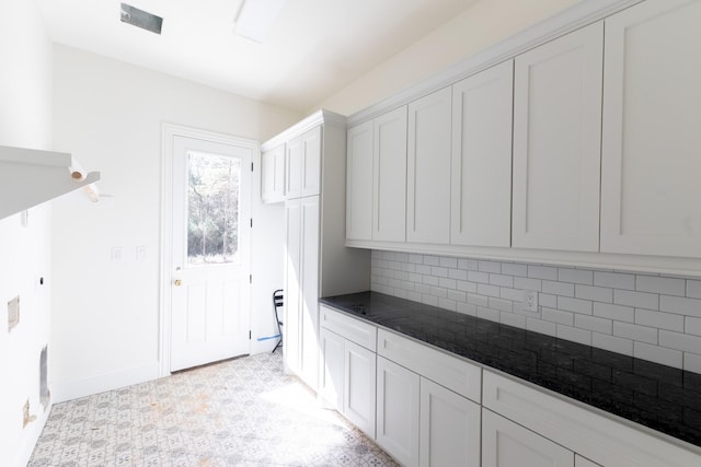 kitchen with decorative backsplash, baseboards, and white cabinets