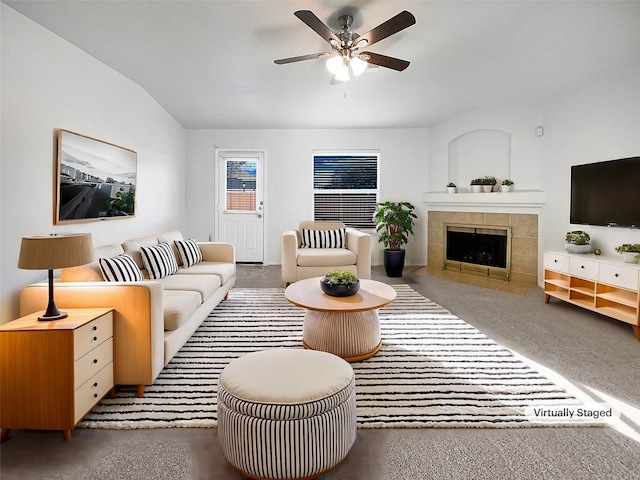 living room featuring a tiled fireplace, finished concrete floors, and a ceiling fan