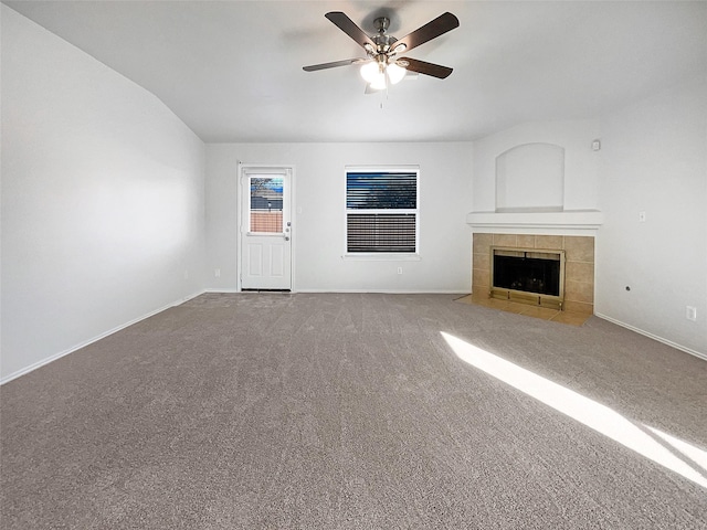 unfurnished living room with a tiled fireplace, a ceiling fan, baseboards, and carpet floors