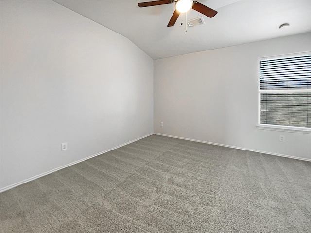 carpeted empty room with visible vents, baseboards, ceiling fan, and vaulted ceiling