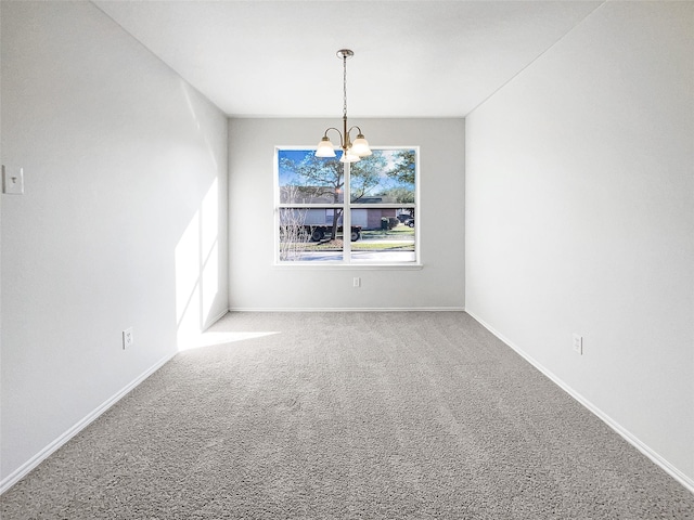 carpeted spare room with baseboards and a notable chandelier