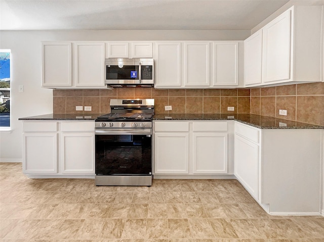 kitchen with tasteful backsplash, dark stone countertops, appliances with stainless steel finishes, and white cabinetry