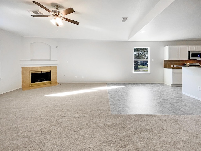 unfurnished living room featuring visible vents, light carpet, ceiling fan, and a fireplace