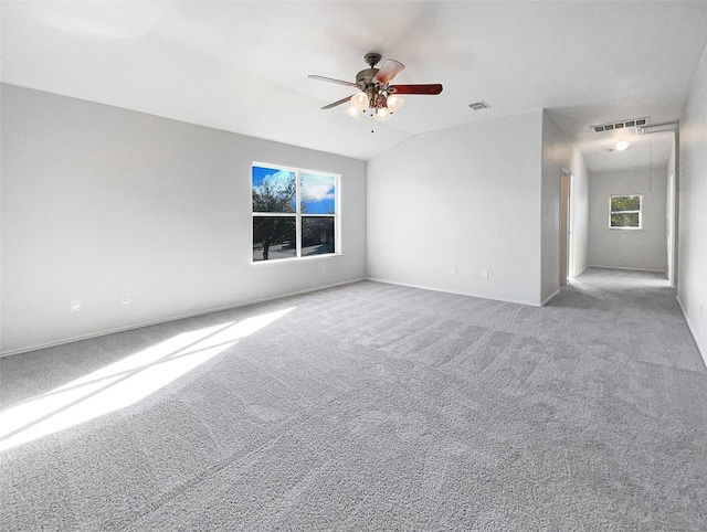 carpeted spare room with visible vents, baseboards, a ceiling fan, and vaulted ceiling