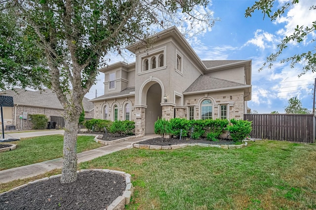 view of front facade featuring stucco siding, stone siding, a front yard, and fence