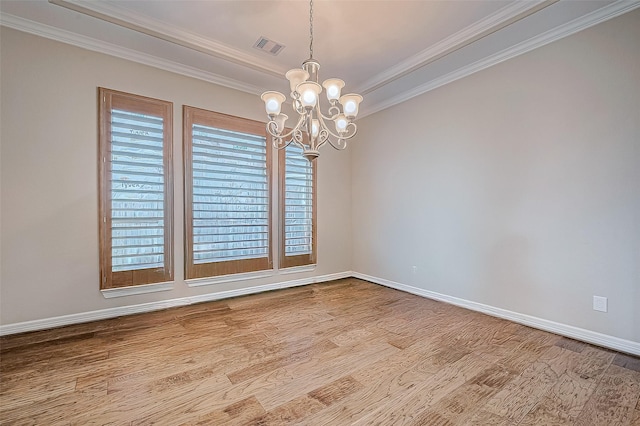 unfurnished room with visible vents, a notable chandelier, wood finished floors, crown molding, and baseboards