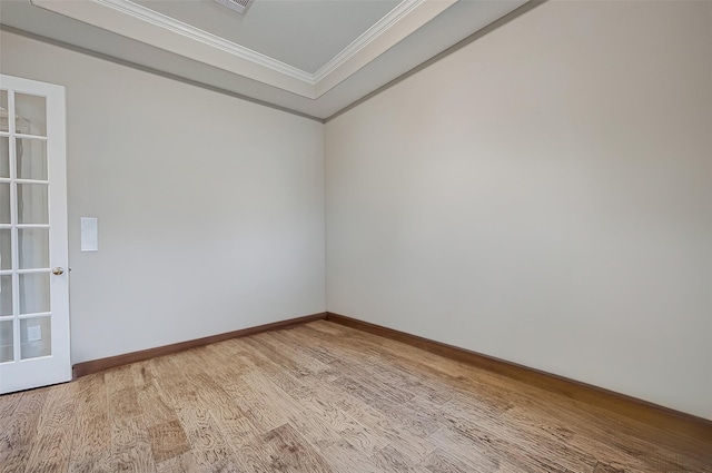 spare room with crown molding, baseboards, and light wood finished floors