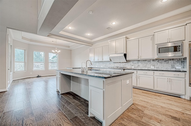 kitchen featuring decorative backsplash, crown molding, light wood finished floors, and appliances with stainless steel finishes