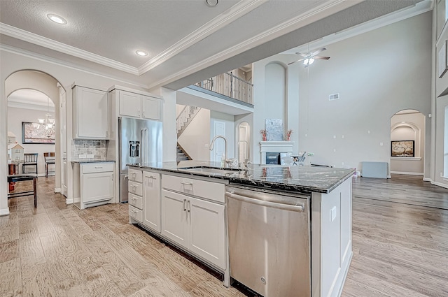 kitchen with a glass covered fireplace, light wood-style floors, arched walkways, and stainless steel appliances