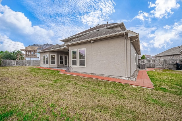 back of property with stucco siding, a lawn, a fenced backyard, and a gate