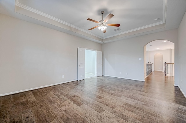 empty room with visible vents, arched walkways, baseboards, and wood finished floors