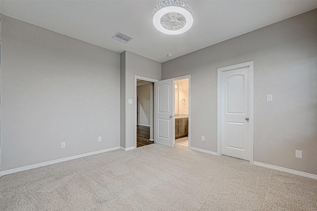 unfurnished bedroom with light carpet, visible vents, connected bathroom, and baseboards