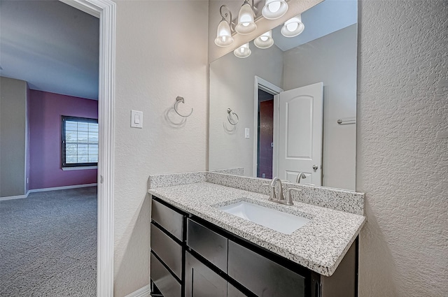 bathroom featuring baseboards, vanity, and a textured wall