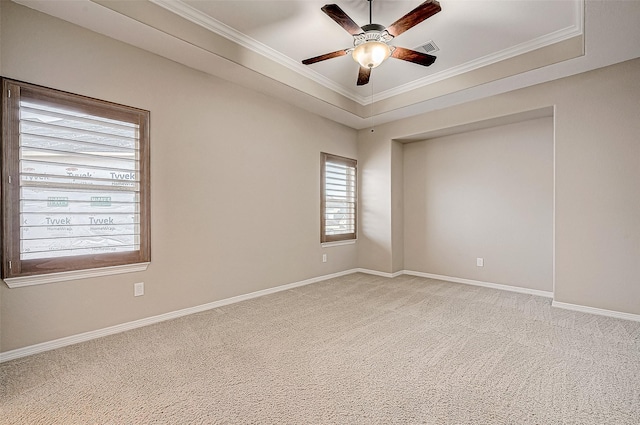 empty room featuring a ceiling fan, visible vents, baseboards, ornamental molding, and light carpet