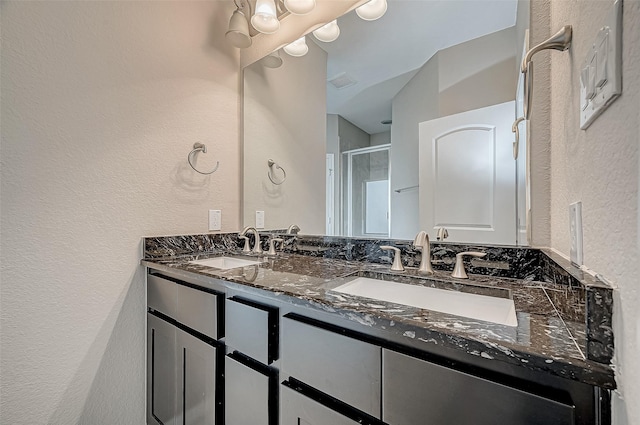 full bathroom with double vanity, visible vents, a stall shower, and a sink