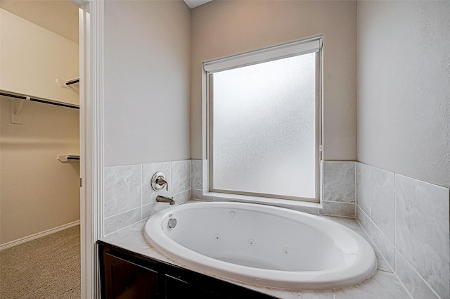 bathroom featuring a walk in closet and a tub with jets