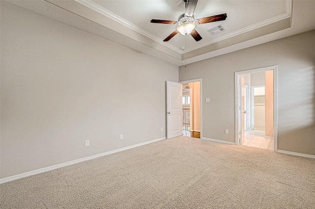 unfurnished bedroom featuring visible vents, crown molding, baseboards, light colored carpet, and a tray ceiling