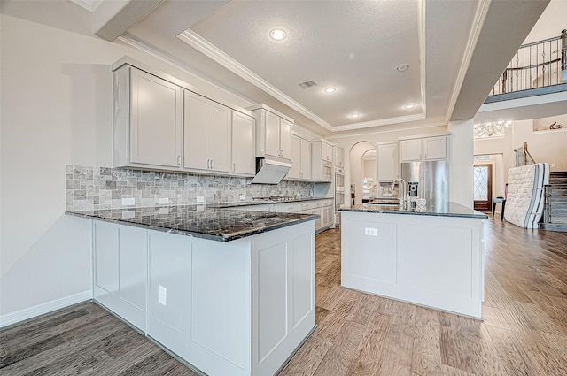 kitchen featuring light wood finished floors, visible vents, tasteful backsplash, dark stone counters, and appliances with stainless steel finishes