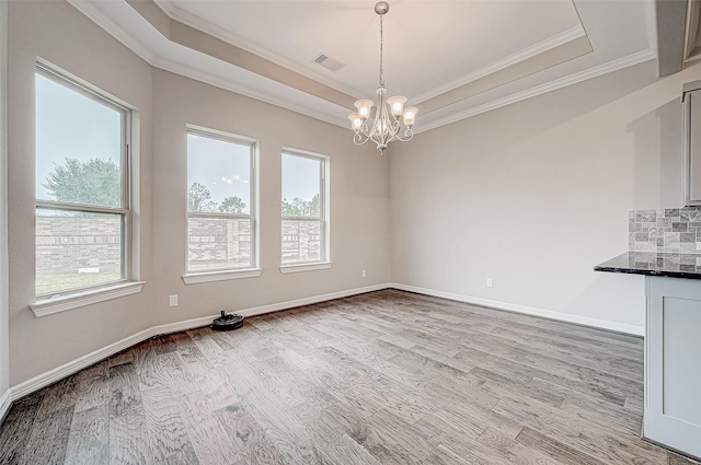 unfurnished dining area featuring a tray ceiling, plenty of natural light, visible vents, and a chandelier