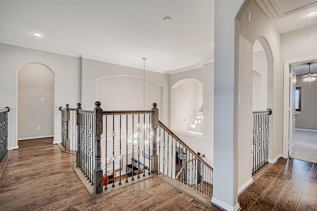 corridor featuring attic access, crown molding, wood finished floors, and an upstairs landing