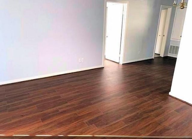 spare room featuring dark wood-type flooring, baseboards, and visible vents