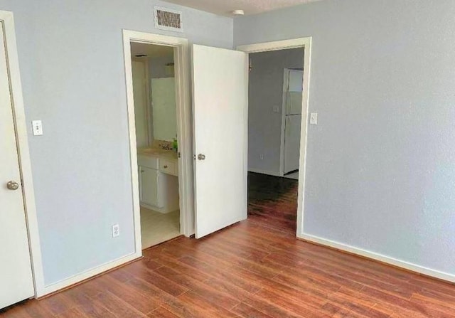 spare room with wood finished floors, visible vents, and baseboards