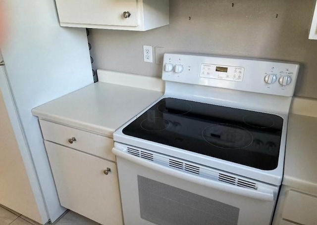 kitchen with white appliances, white cabinets, light tile patterned floors, and light countertops