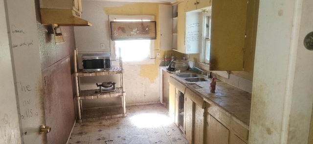 kitchen featuring stainless steel microwave, tile countertops, and a sink