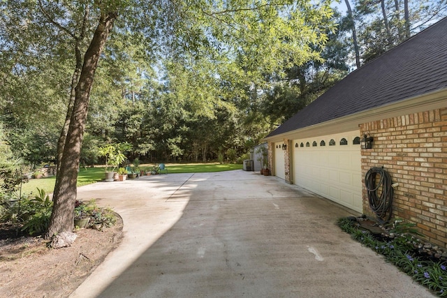 view of property exterior featuring brick siding, driveway, and a shingled roof