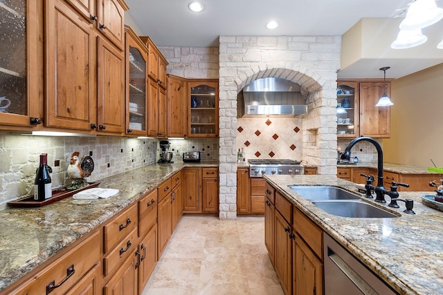 kitchen featuring backsplash, decorative light fixtures, brown cabinets, appliances with stainless steel finishes, and a sink