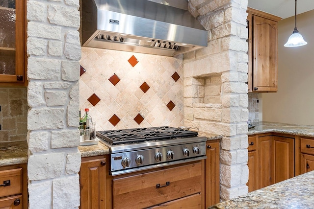 kitchen with tasteful backsplash, ventilation hood, brown cabinetry, glass insert cabinets, and stainless steel gas cooktop